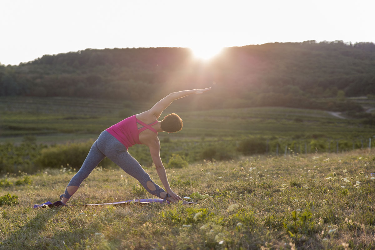 Vitálka - jóga  pri zápede slnka - ženy cvičiace na zelenej lúke.