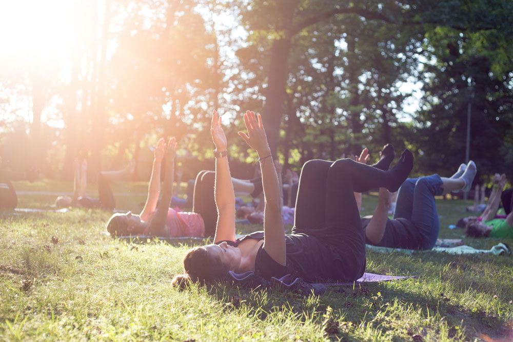 Vitálka - jóga v parku pri altánku - ľudia cvičiaci na zelenej lúke v parku.