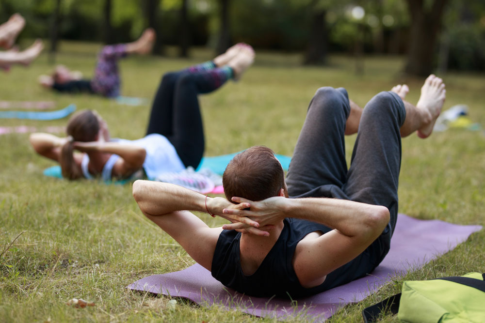 Vitálka - jóga v parku pri altánku - ľudia cvičiaci jógu na trávnatej ploche.
