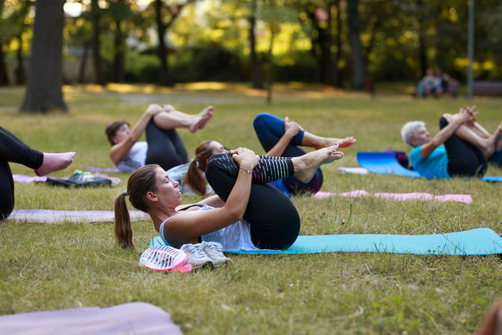 Vitálka - jóga v parku pri altánku - ľudia cvičiaci jógu na trávnatej ploche.