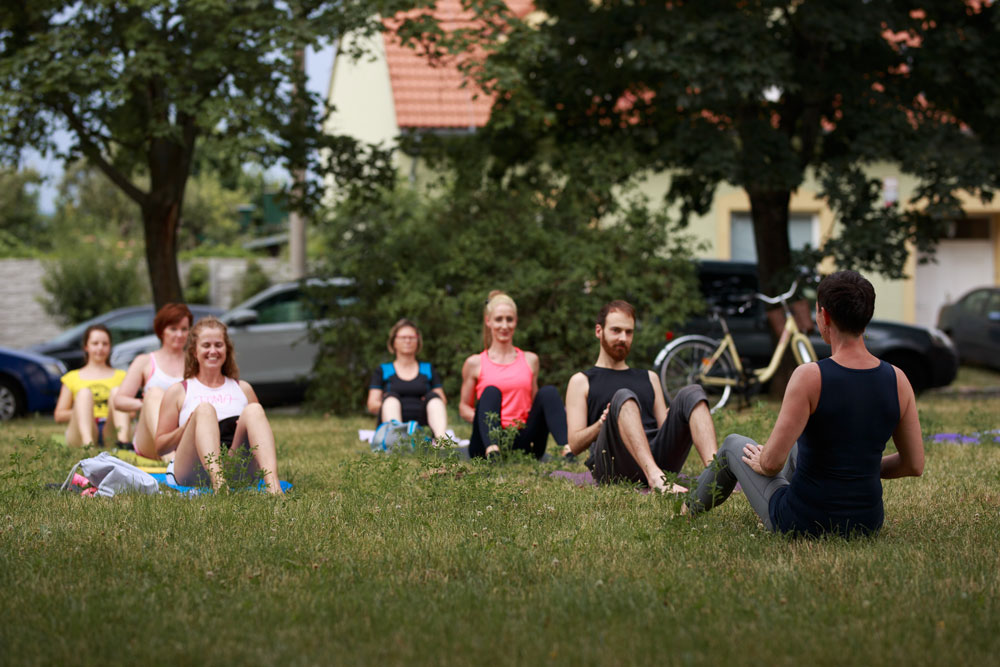 Vitálka - Pilates v meste - ľudia cvičiaci pilates na trávnatej ploche.